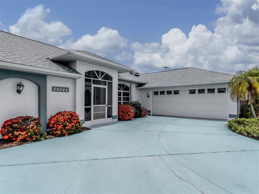 A single-story house with a white exterior, a blue driveway, and a two-car garage — 25244 RAMPART BOULEVARD, PUNTA GORDA, FL