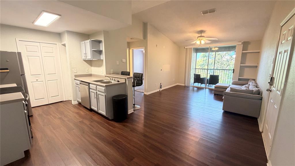 An open-concept kitchen and living area feature wood-look flooring, light cabinetry, and a balcony view — 8849 LATREC AVENUE UNIT 4202, ORLANDO, FL