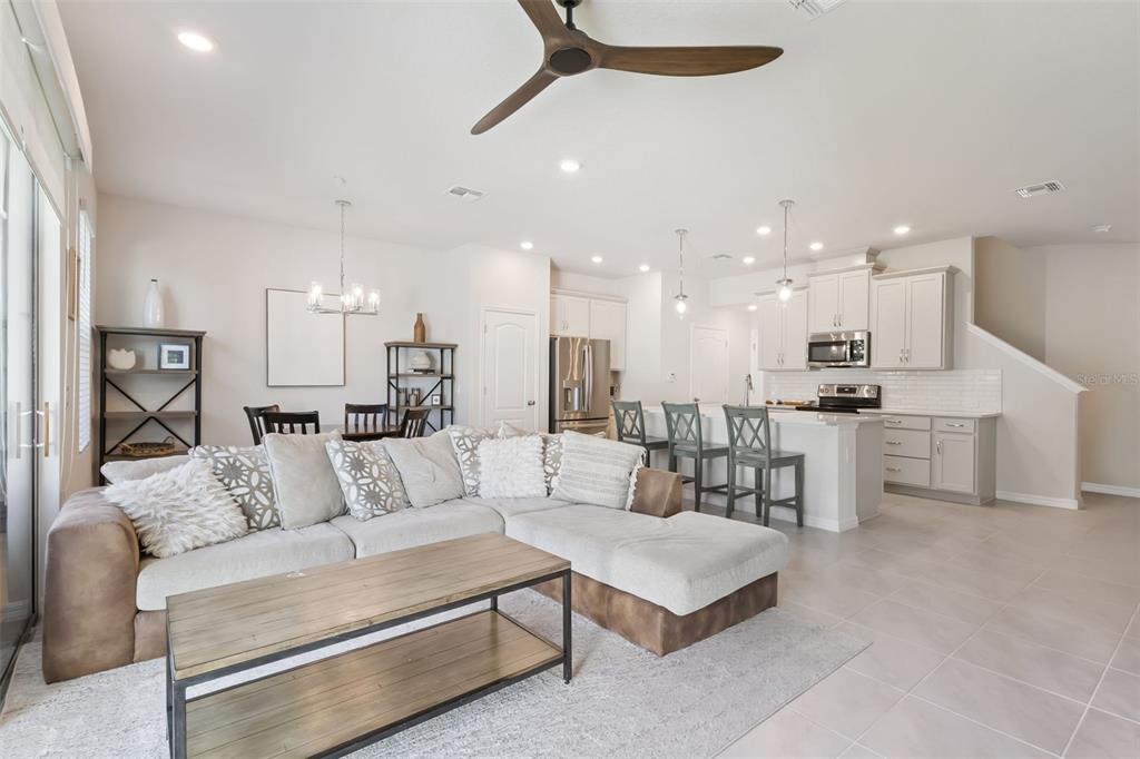 An open-concept living room and kitchen featuring a sectional sofa, dining area, and island seating — 637 ASTERA WINDS LANE, LAKE MARY, FL