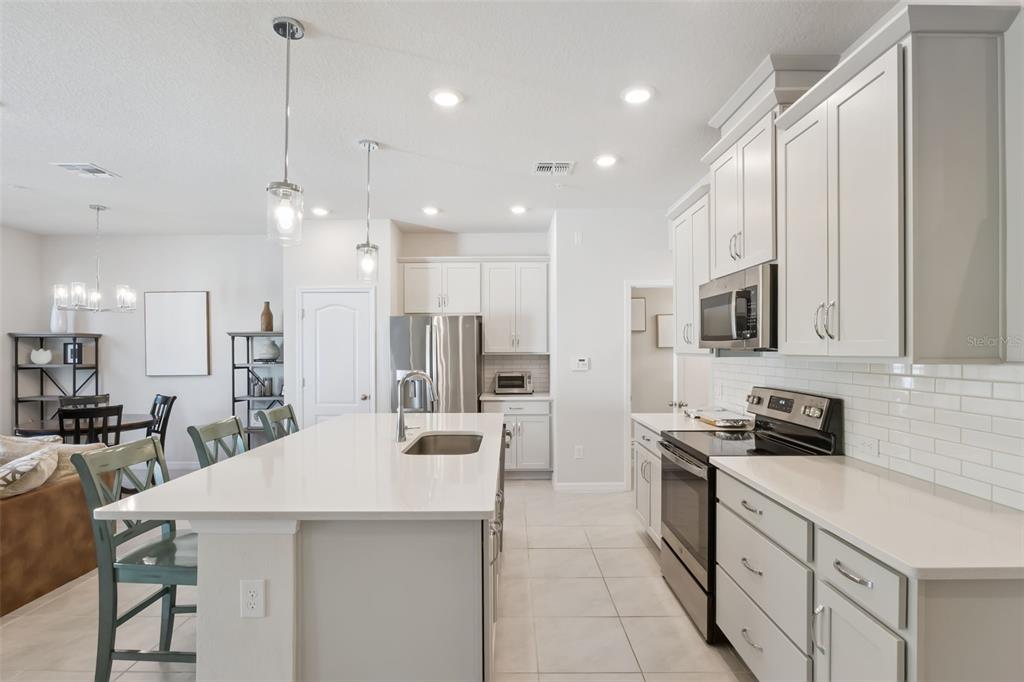 A modern kitchen features white cabinetry, a large center island, and stainless steel appliances — 637 ASTERA WINDS LANE, LAKE MARY, FL