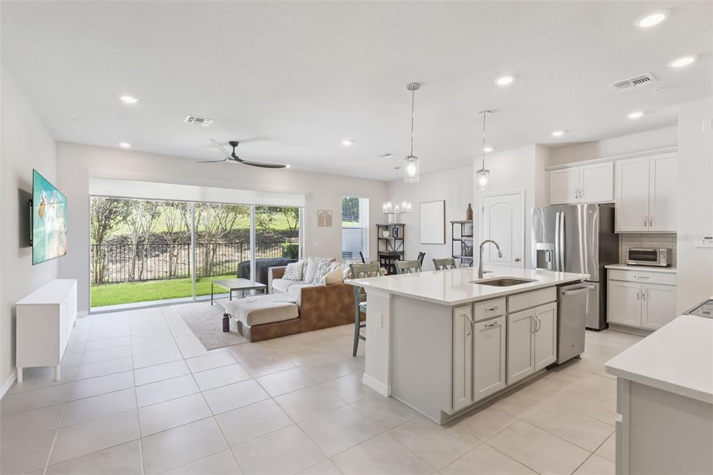 An open-concept kitchen and living area with light tile floors, white cabinetry, and sliding doors — 637 ASTERA WINDS LANE, LAKE MARY, FL