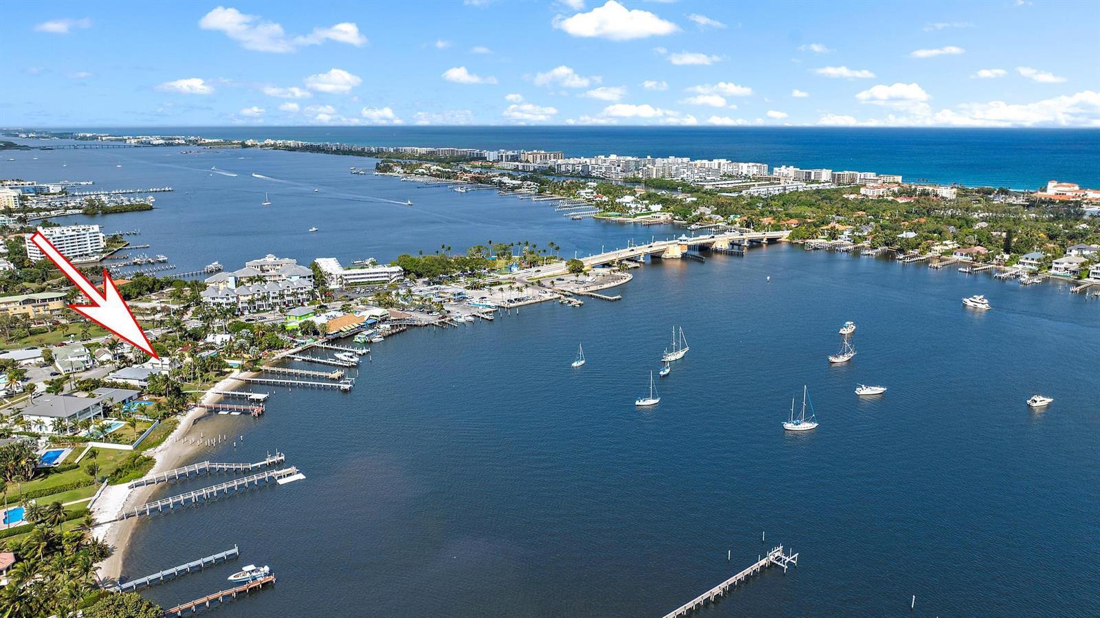 An aerial view shows a waterfront property with docks, a sandy beach, and a bridge — 122 S Lake Drive, Lantana FL 33462, LANTANA, FL