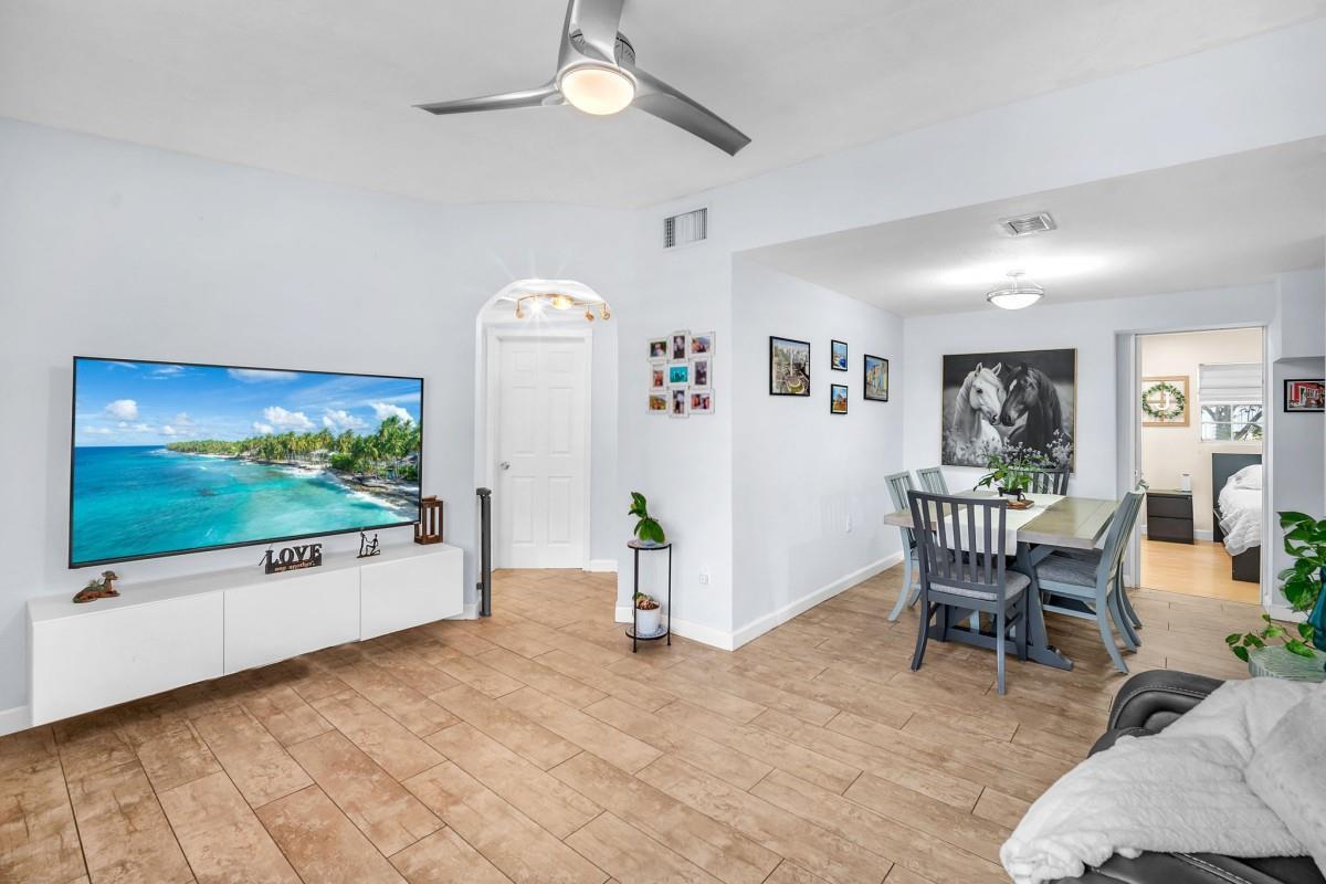 A living room with a wall-mounted television, white media console, and an adjacent dining area — 404 S 62nd Terrace, Hollywood FL 33023, HOLLYWOOD, FL