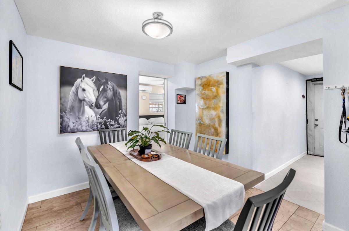A dining room features a wooden table, grey chairs, horse artwork, and light-colored flooring — 404 S 62nd Terrace, Hollywood FL 33023, HOLLYWOOD, FL