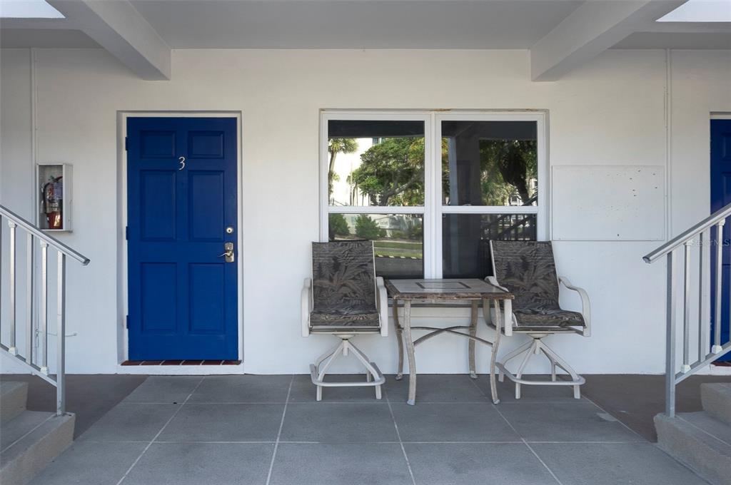 A blue door labeled number three sits next to a window and patio furniture — 7151 SUNSET WAY UNIT 3, ST PETE BEACH, FL