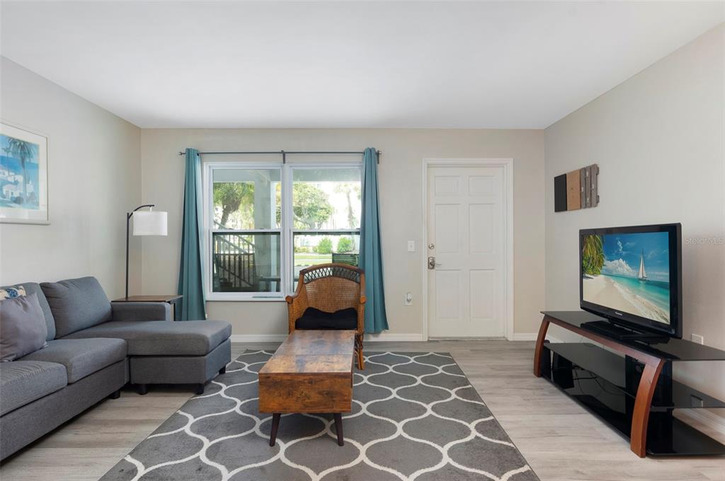 A living room features a gray sectional sofa, a wooden coffee table, and a television — 7151 SUNSET WAY UNIT 3, ST PETE BEACH, FL