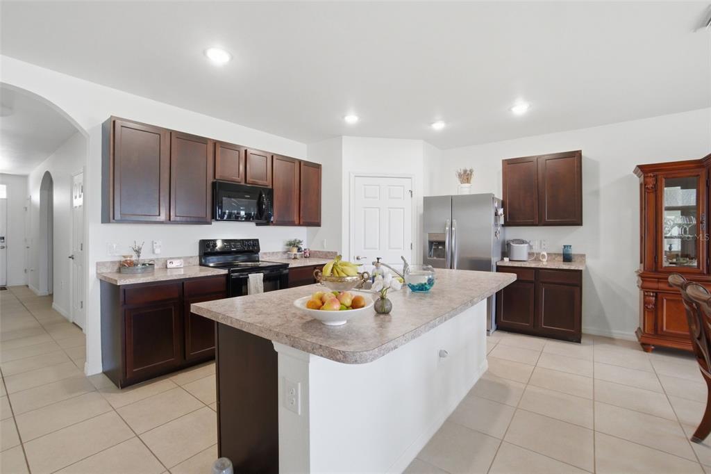 A kitchen with dark wood cabinets, a central island, stainless steel appliances, and tile flooring — 3422 CANCUN COURT, CAPE CORAL, FL