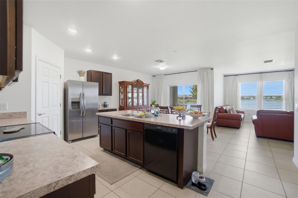 A kitchen with dark wood cabinets and a central island overlooks a living area — 3422 CANCUN COURT, CAPE CORAL, FL