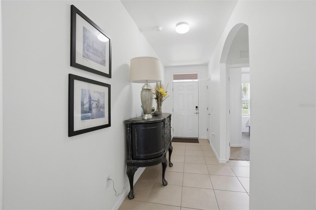 A tiled entryway features a dark wooden cabinet, a table lamp, and two framed pictures — 3422 CANCUN COURT, CAPE CORAL, FL