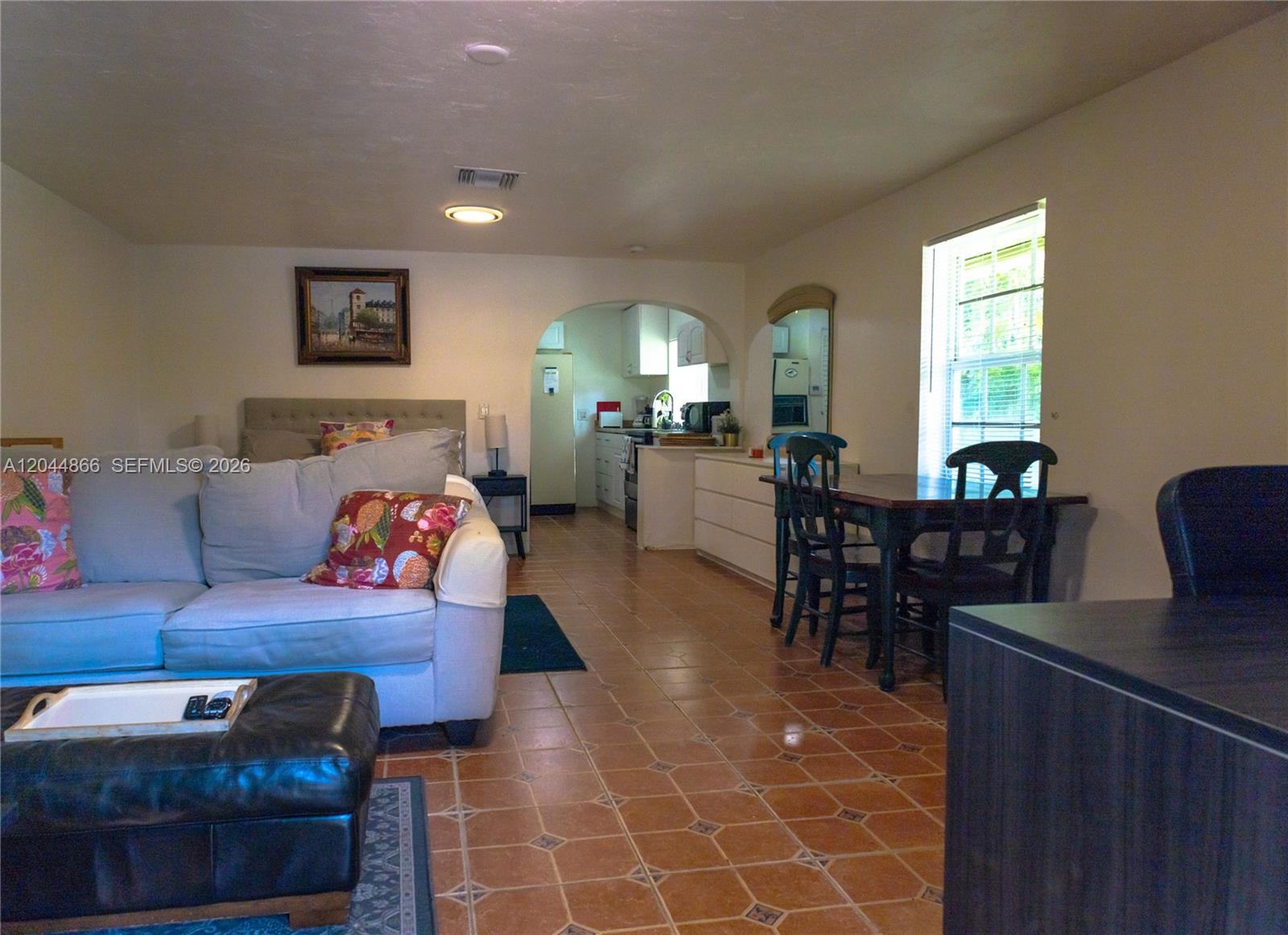 This open-concept living area features a sofa, dining set, and an arched kitchen entrance — 271 NE 154th St # 1, Miami FL 33162, MIAMI, FL