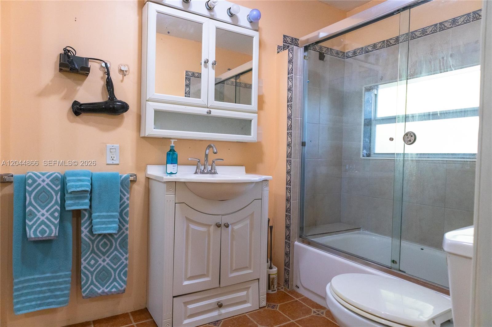 A bathroom features a white vanity, a medicine cabinet, a shower-tub combo, and peach walls — 271 NE 154th St # 1, Miami FL 33162, MIAMI, FL