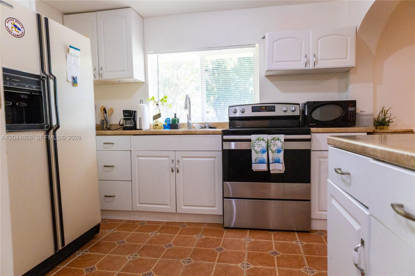 A kitchen features white cabinets, stainless steel appliances, and brown patterned tile flooring — 271 NE 154th St # 1, Miami FL 33162, MIAMI, FL