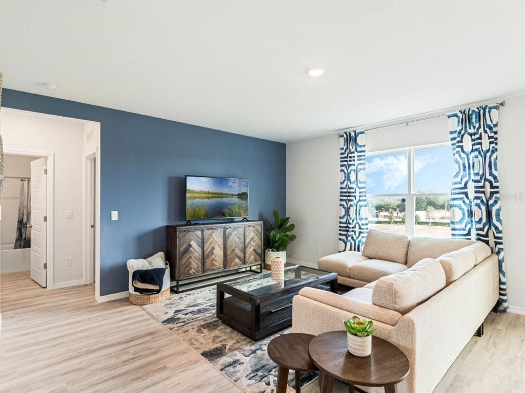 A living room features a blue accent wall, a television, and a beige sectional sofa — 3958 LIMEKLIN FALLS LOOP, DAVENPORT, FL