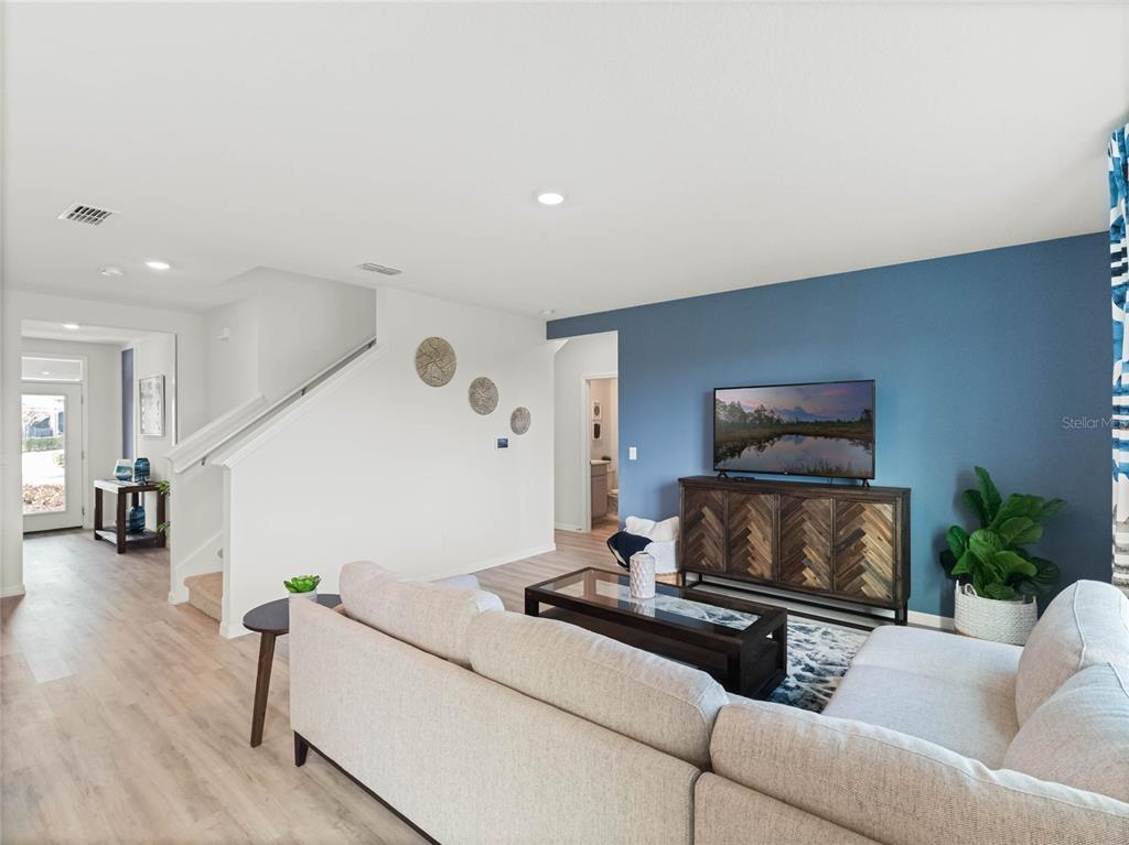 A living room features a blue accent wall, a sectional sofa, and a wooden console — 3958 LIMEKLIN FALLS LOOP, DAVENPORT, FL
