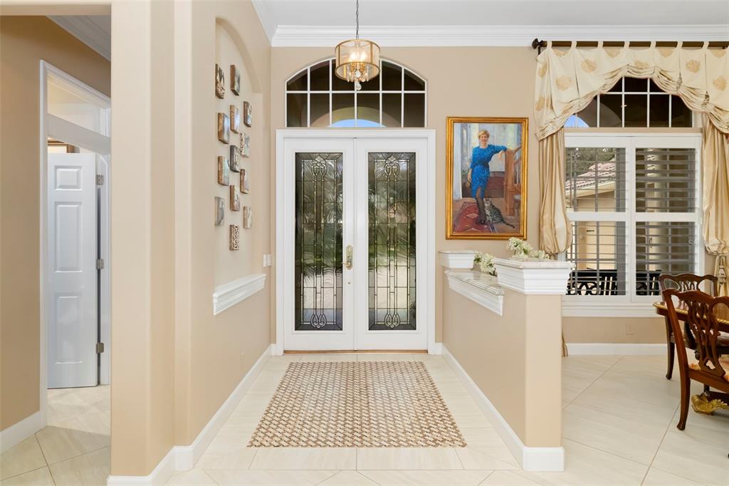 An entryway with a double glass door, tile flooring, a portrait, and a half wall — 7215 CHATSWORTH COURT, BRADENTON, FL