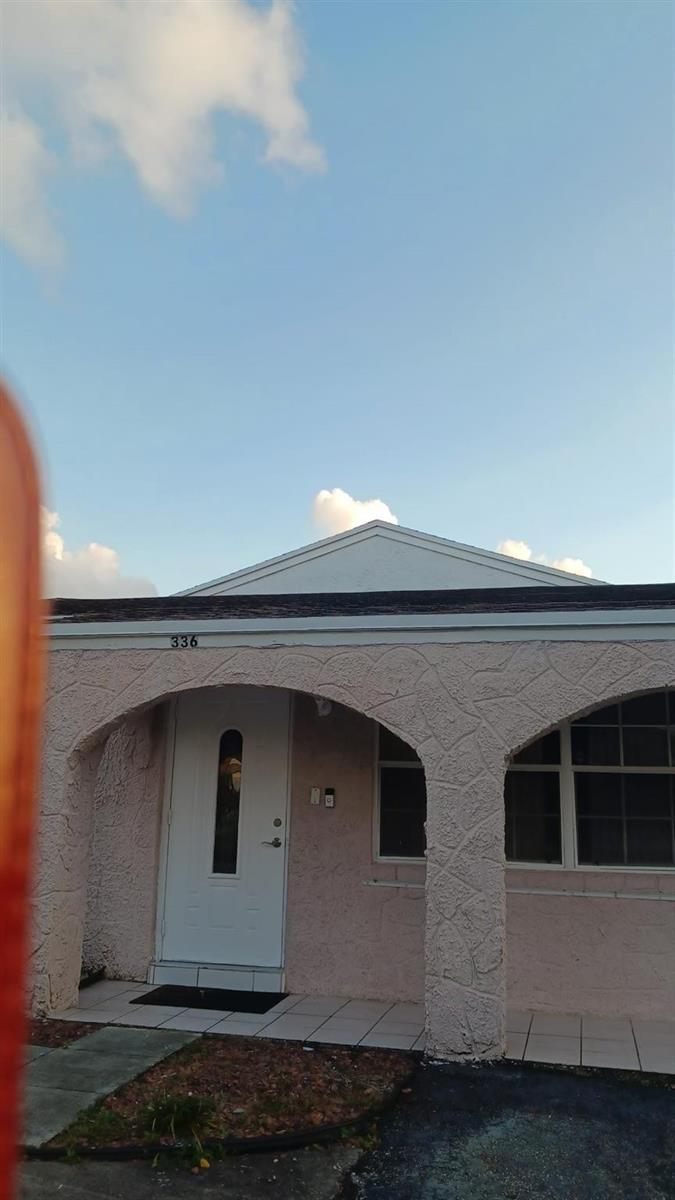 A pink stucco house exterior features a covered porch with arched columns and a white door — 336 NW 7th Court, Deerfield Beach FL 33441, DEERFIELD BEACH, FL