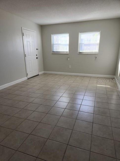 An empty room features light-colored walls, a white door, and beige tiled flooring — 817 SKY LAKE CIRCLE UNIT A, ORLANDO, FL