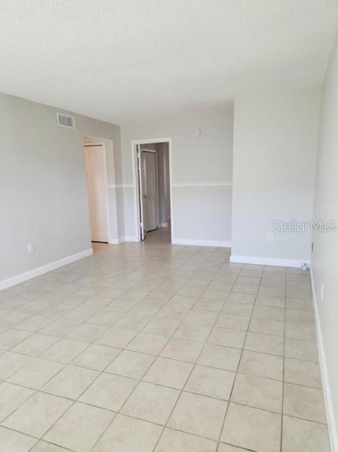 An empty room with light-colored walls and beige tile flooring features a doorway — 817 SKY LAKE CIRCLE UNIT A, ORLANDO, FL