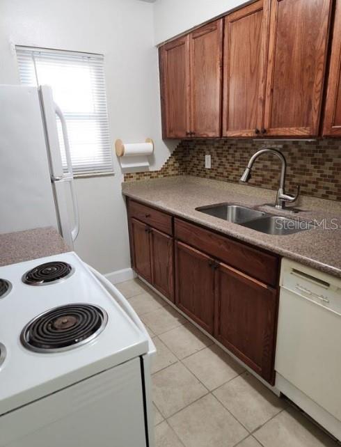 A kitchen features wood cabinets, a white stove, a double sink, and a tiled backsplash — 817 SKY LAKE CIRCLE UNIT A, ORLANDO, FL