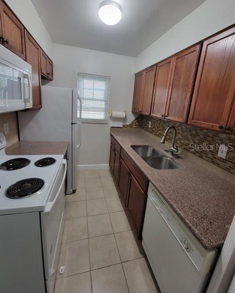 A galley kitchen features wood cabinets, granite countertops, white appliances, and a tiled backsplash — 817 SKY LAKE CIRCLE UNIT A, ORLANDO, FL