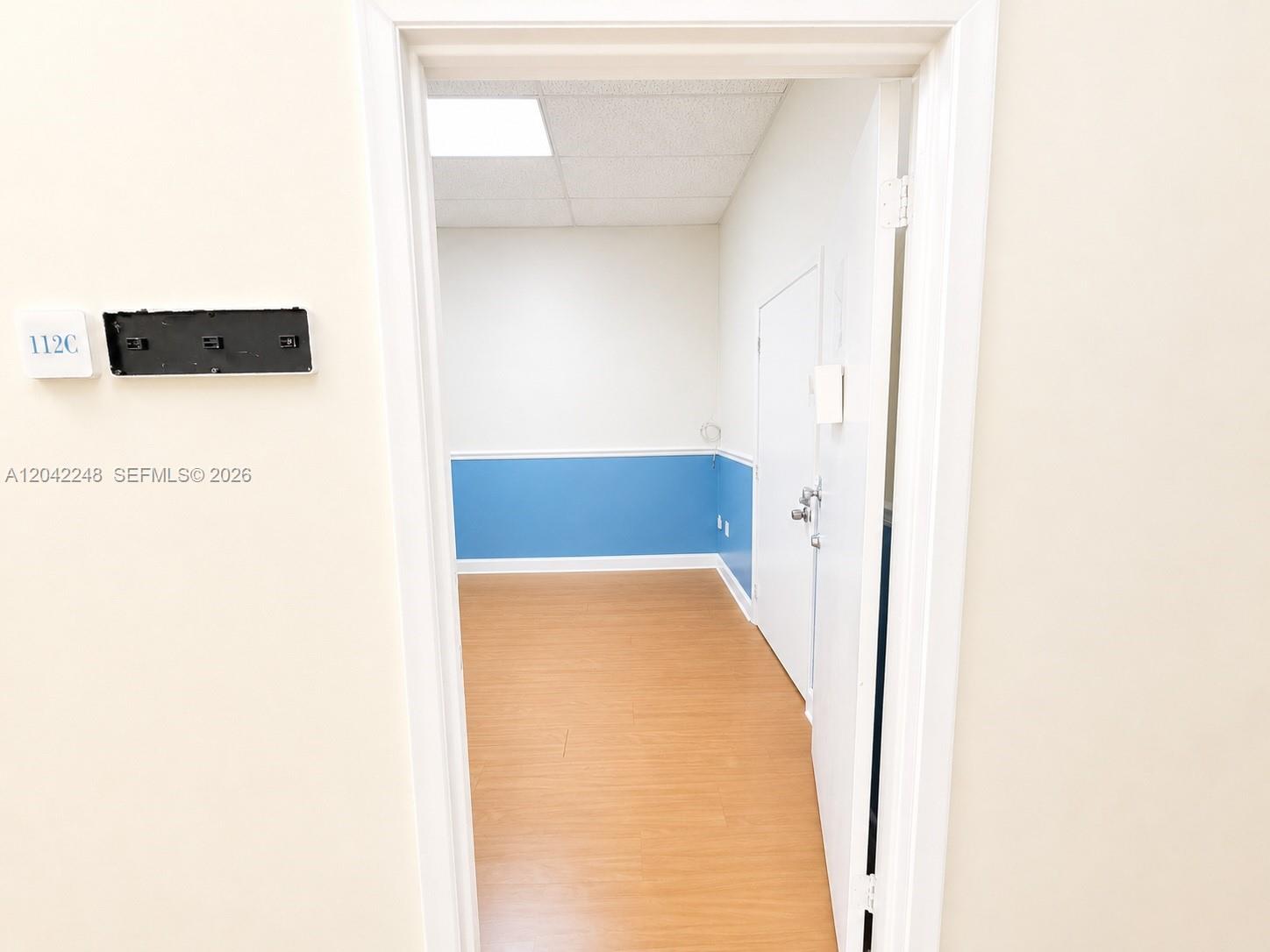 An office space features light wood-look flooring, a blue wainscot, and a white door — 10240 SW 56th St # C, Miami FL 33165, MIAMI, FL