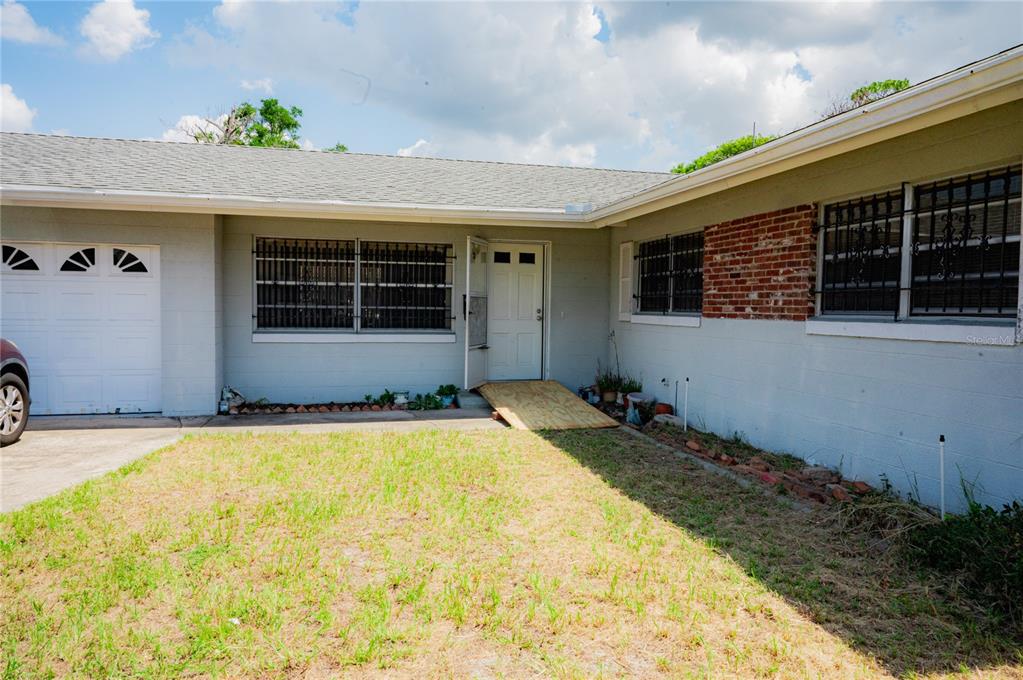 The exterior of a single-story house features a garage, a brick accent wall, and a ramp — 2705 SHERINGHAM ROAD UNIT 6, ORLANDO, FL