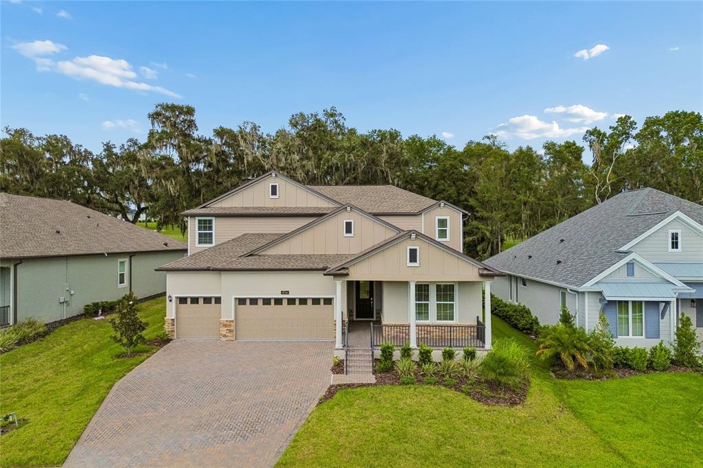 A two-story suburban house features a three-car garage, a covered front porch, and a paved driveway — 4794 SOUTHERN VALLEY LOOP, BROOKSVILLE, FL