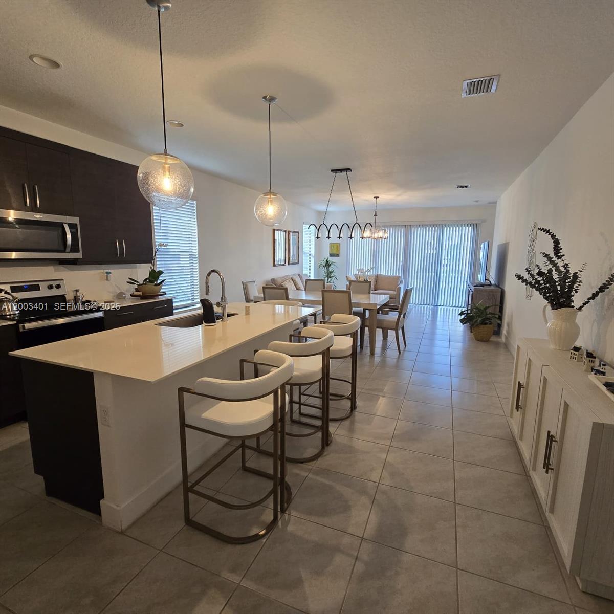 A modern open-concept kitchen and dining area featuring a large island with bar seating — 5615 CARRARA DR, Ave Maria FL 34142, AVE MARIA, FL