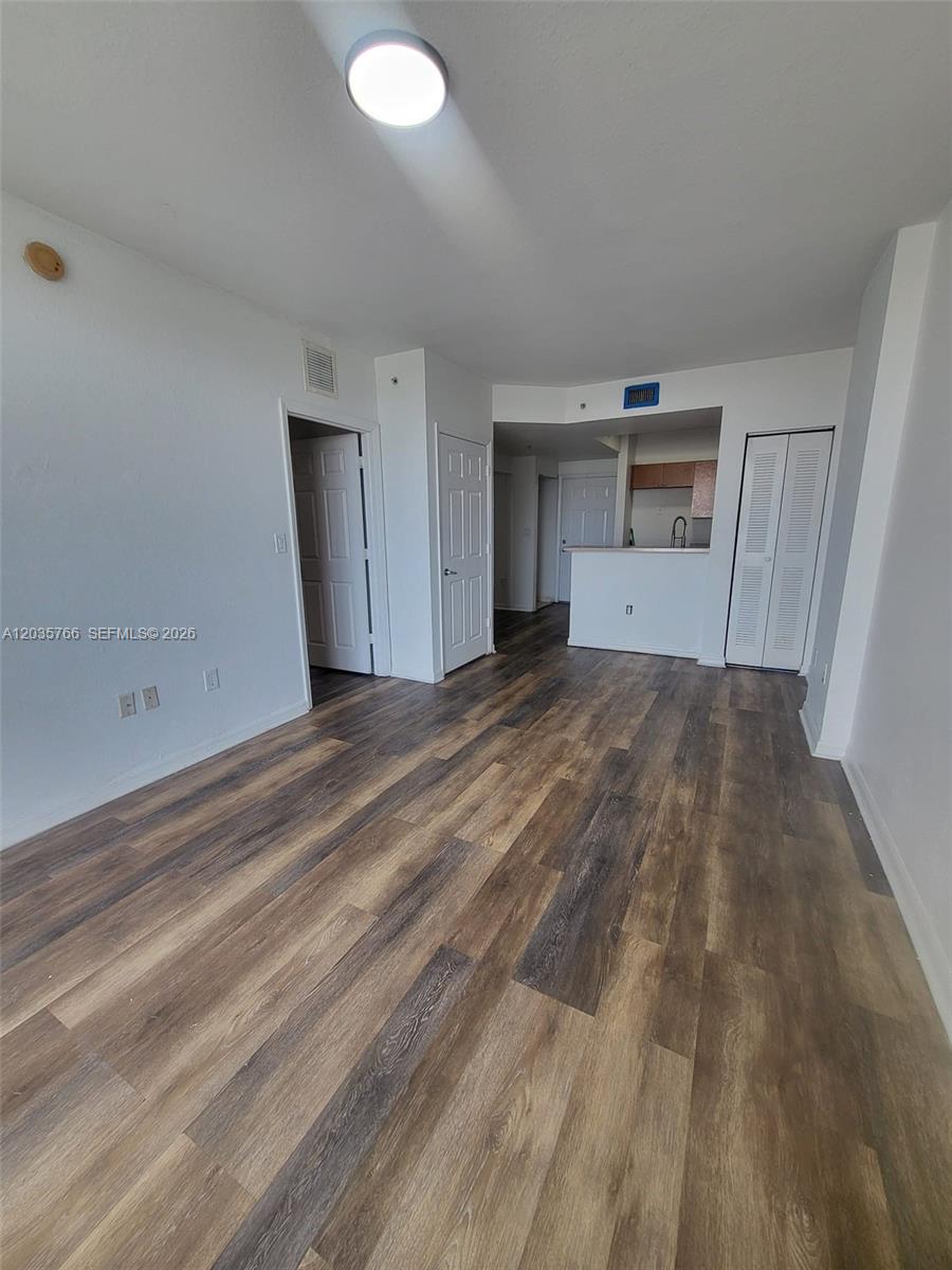 This living area features wood-look flooring, white walls, and an open kitchen pass-through — 120 SW 8th Ave # 502, Miami FL 33130, MIAMI, FL