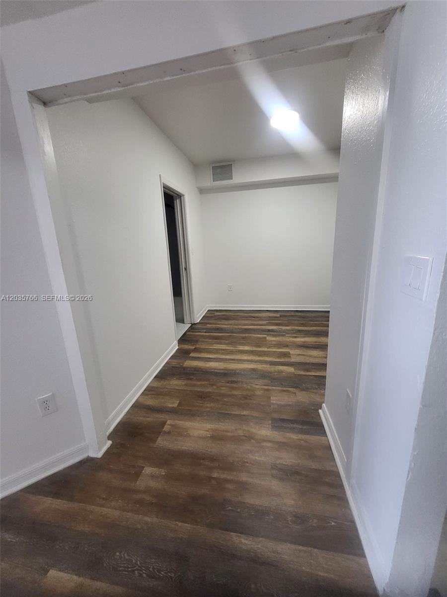 A room with wood-look flooring and white walls is viewed through a wide doorway — 120 SW 8th Ave # 502, Miami FL 33130, MIAMI, FL