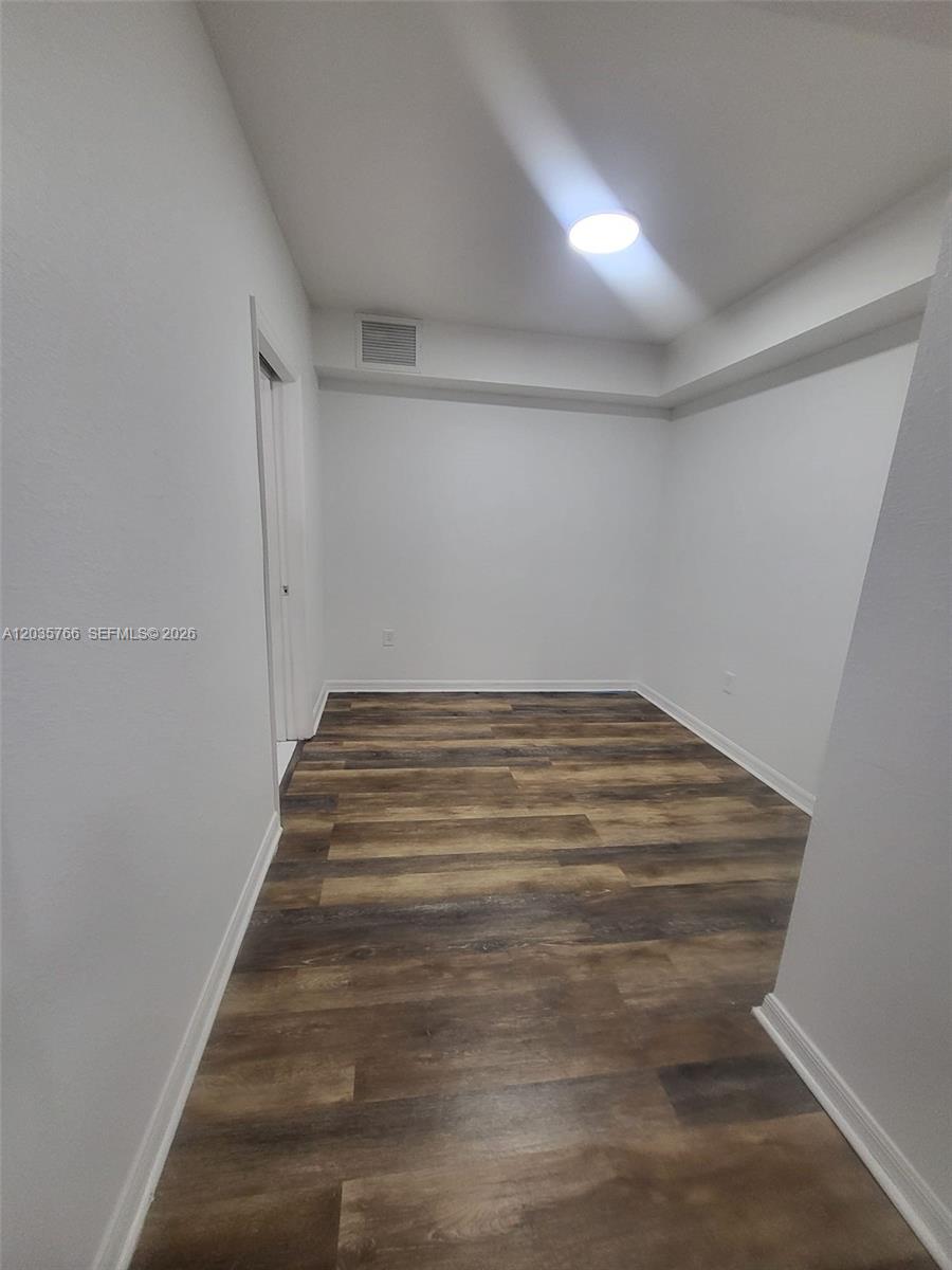 An empty room features white walls, a recessed ceiling light, and wood-look plank flooring — 120 SW 8th Ave # 502, Miami FL 33130, MIAMI, FL