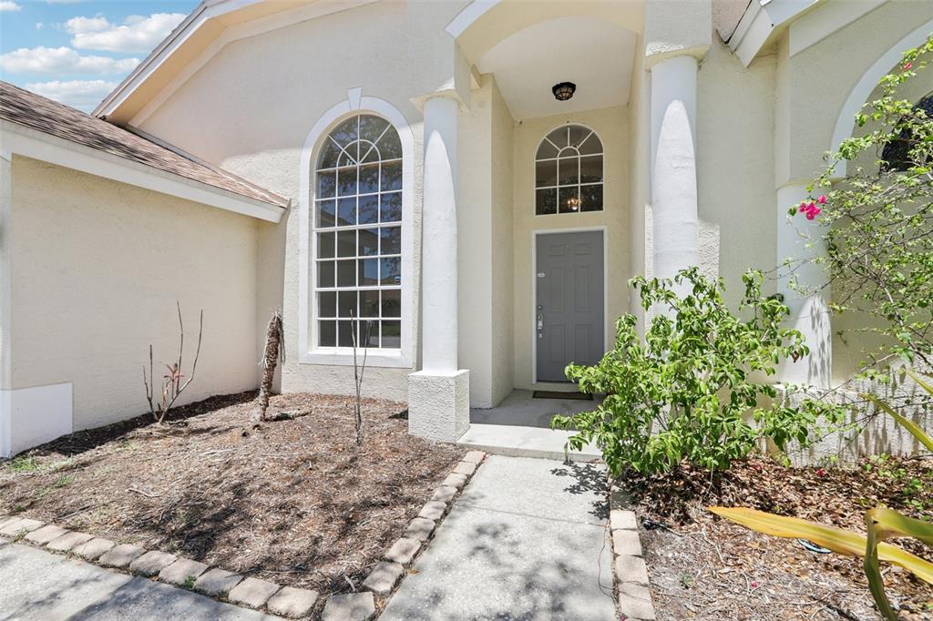 The exterior of a house features a gray front door, white columns, and arched windows — 9029 WESTBAY BOULEVARD, TAMPA, FL