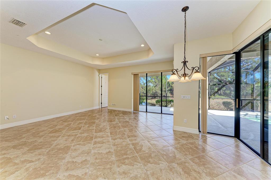 A dining area with tile floors, a tray ceiling, and sliding glass doors to a pool — 650 CRANE PRAIRIE WAY, OSPREY, FL