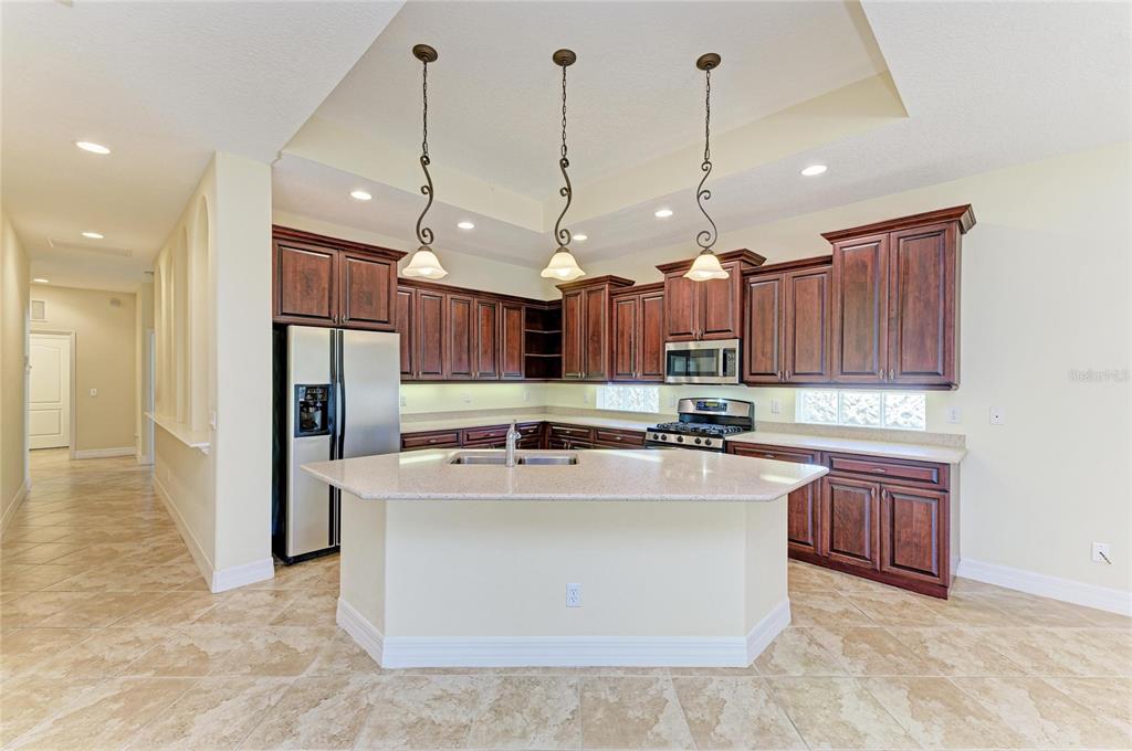 A kitchen with dark wood cabinets, a granite island, and stainless steel appliances — 650 CRANE PRAIRIE WAY, OSPREY, FL