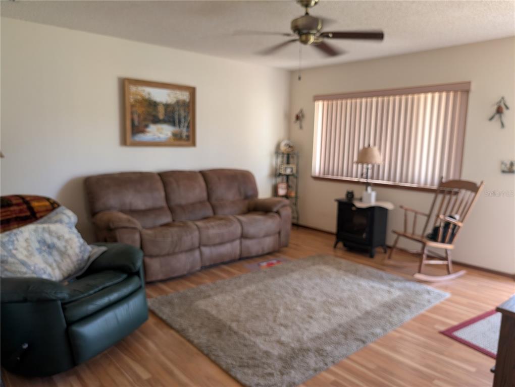 A living room features a brown sofa, a green recliner, a rocking chair, and wood flooring — 8483 SW 106TH PLACE, OCALA, FL