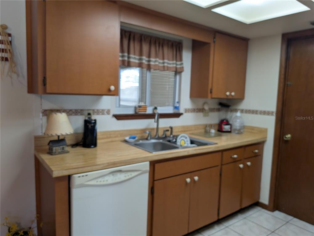 A kitchen features wood cabinets, a laminate countertop, a stainless steel sink, and a dishwasher — 8483 SW 106TH PLACE, OCALA, FL