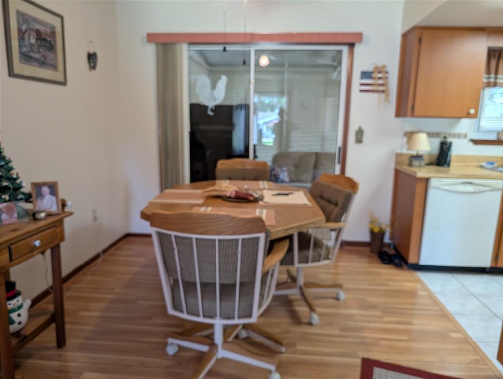 A dining area features a wooden table, rolling chairs, wood flooring, and a sliding glass door — 8483 SW 106TH PLACE, OCALA, FL