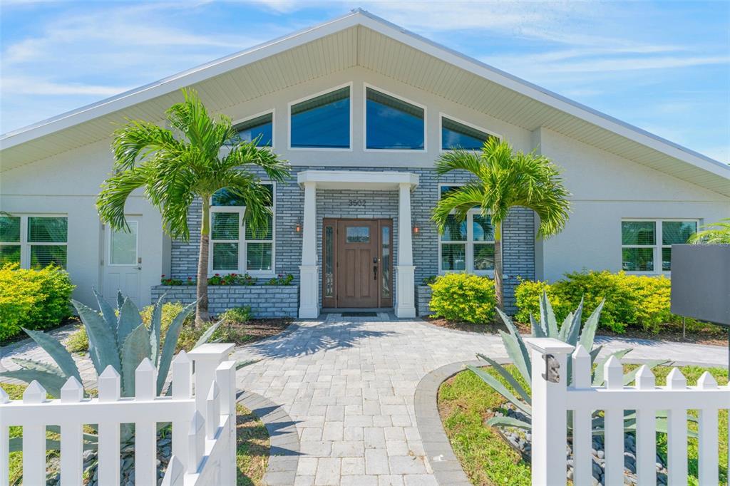 A single-story house features a gray brick facade, a gabled roof, and a white picket fence — 3502 BAHIA VISTA STREET, SARASOTA, FL