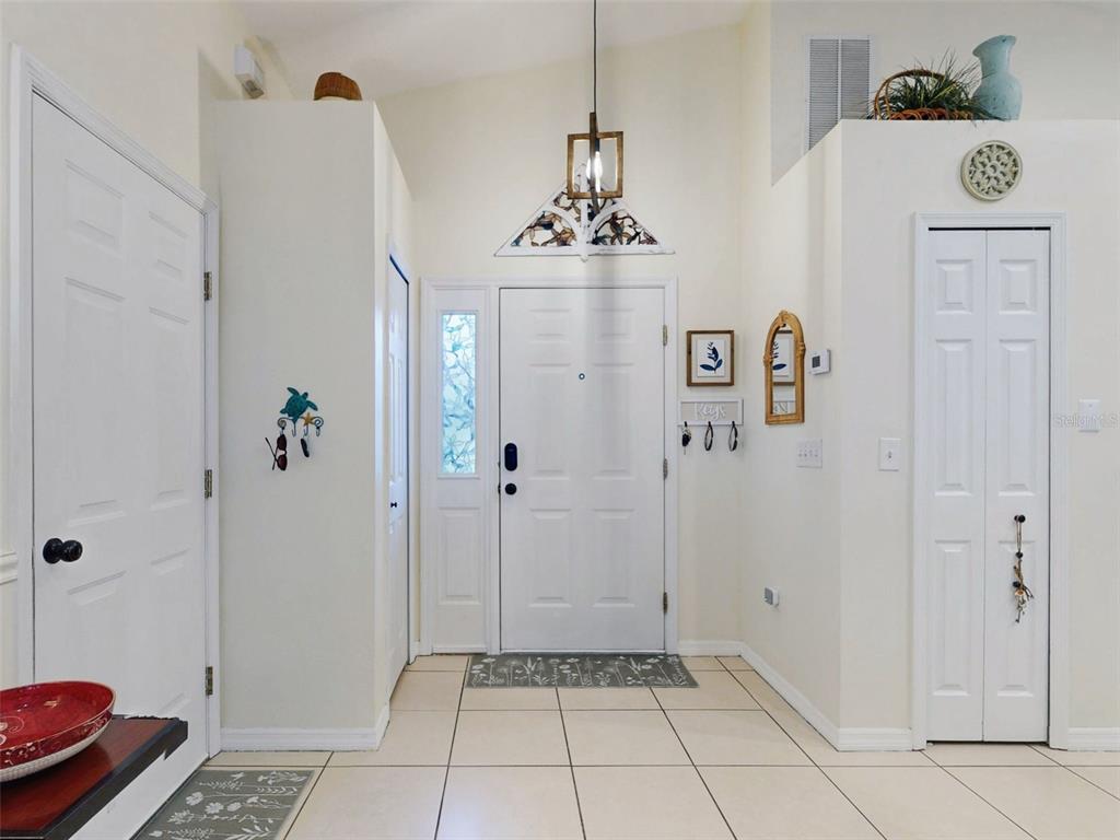 An entryway leads into a kitchen with white cabinets, a blue island, and tile flooring — 242 PINE BLUFF AVENUE UNIT 242, DELAND, FL
