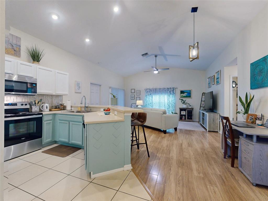 An open-concept kitchen with light blue cabinets and a living area with wood flooring — 242 PINE BLUFF AVENUE UNIT 242, DELAND, FL
