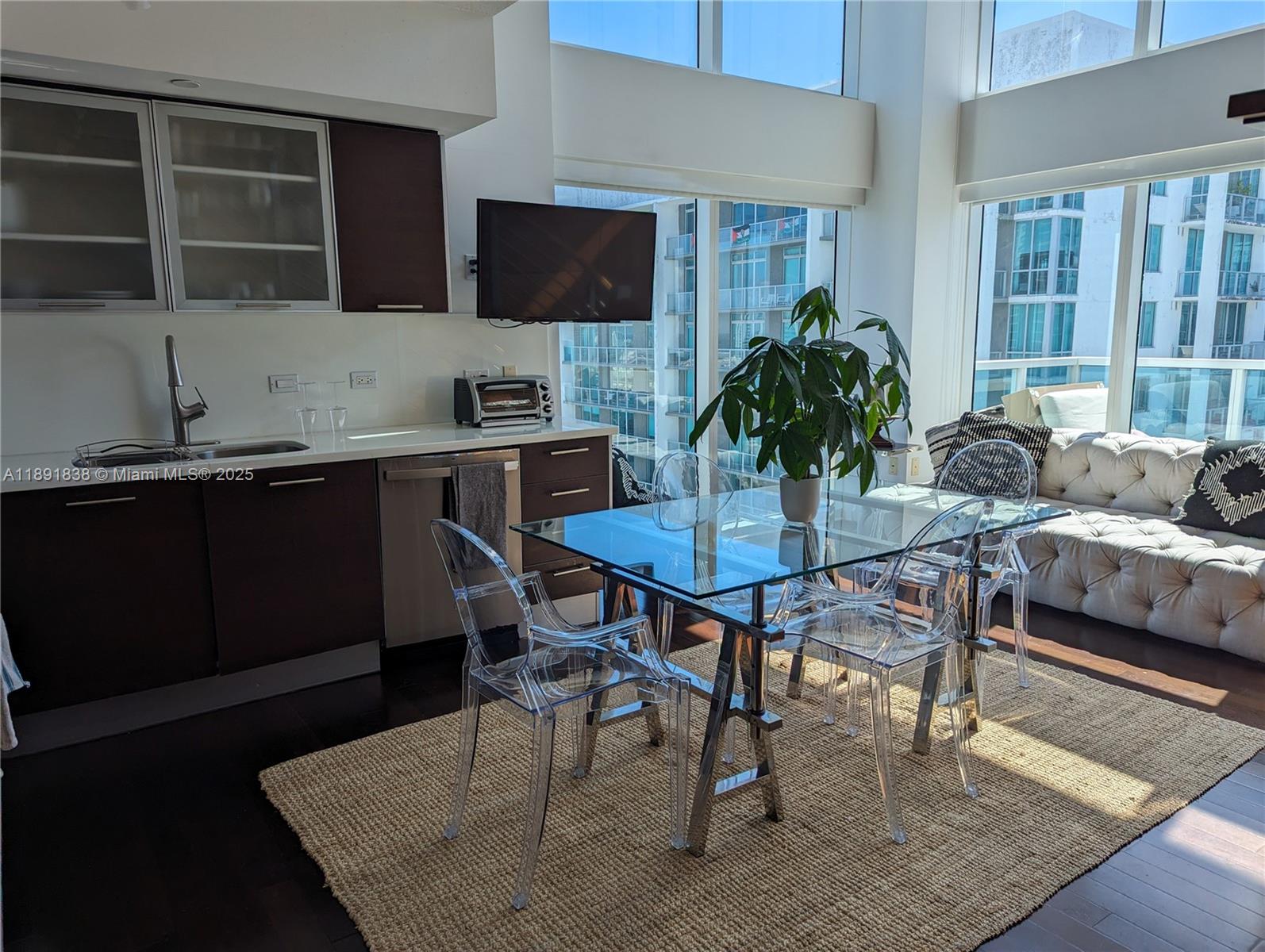 A modern kitchen and dining area features dark cabinetry, a glass table, and floor-to-ceiling windows — 41 SE 5th St # 2302, Miami FL 33131, MIAMI, FL