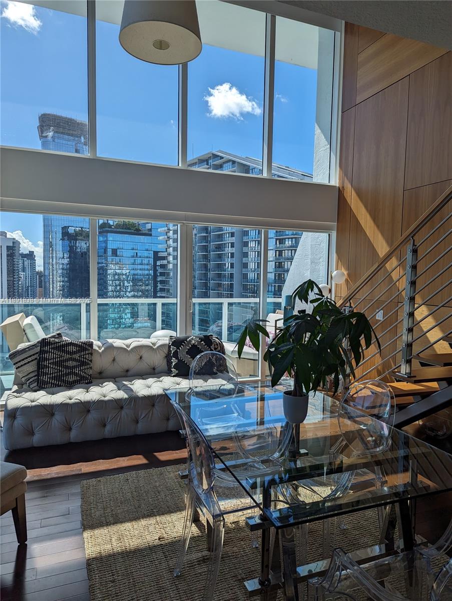 A living and dining area features floor-to-ceiling windows, a tufted sofa, and glass furniture — 41 SE 5th St # 2302, Miami FL 33131, MIAMI, FL