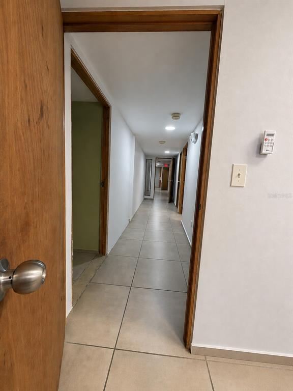A hallway with light-colored tile flooring leads to multiple doorways under recessed ceiling lights — Calle 30 CAPARRA TERRACE SO1300, CAPARRA TERRACE, PR