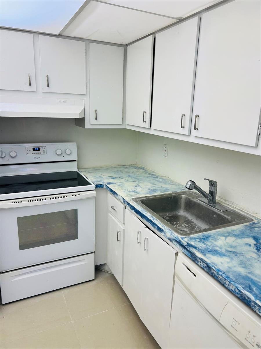 A kitchen features white cabinets, a white stove, a stainless steel sink, and blue countertops — 614 NW 13th Street # 0280, Boca Raton FL 33486, BOCA RATON, FL