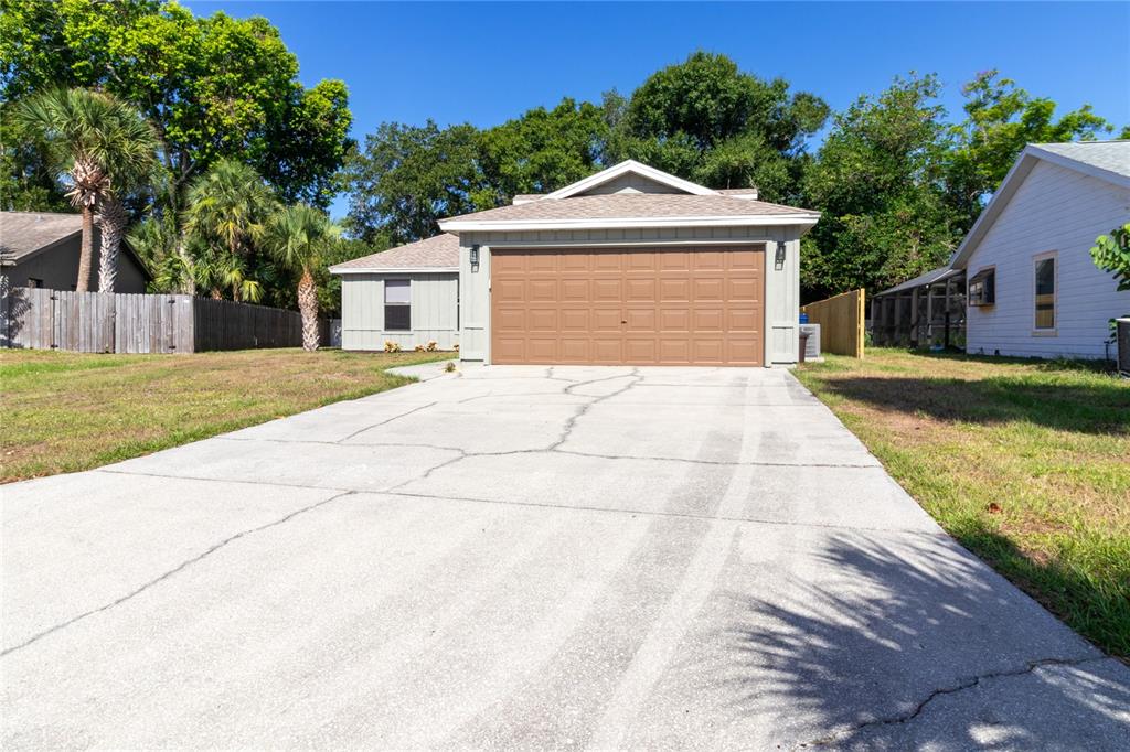 A single-story house with a brown garage door and a cracked concrete driveway — 8232 COUNTRY OAKS COURT, SARASOTA, FL