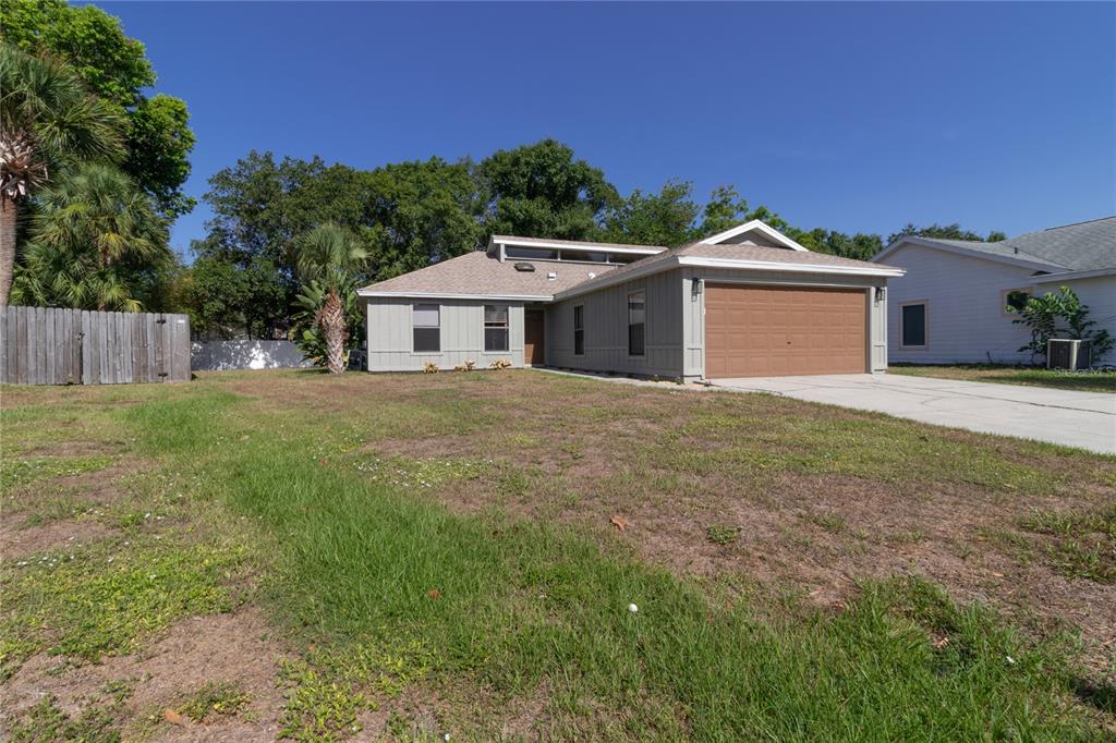 A single-story house with light gray siding, a brown garage door, and a grassy yard — 8232 COUNTRY OAKS COURT, SARASOTA, FL