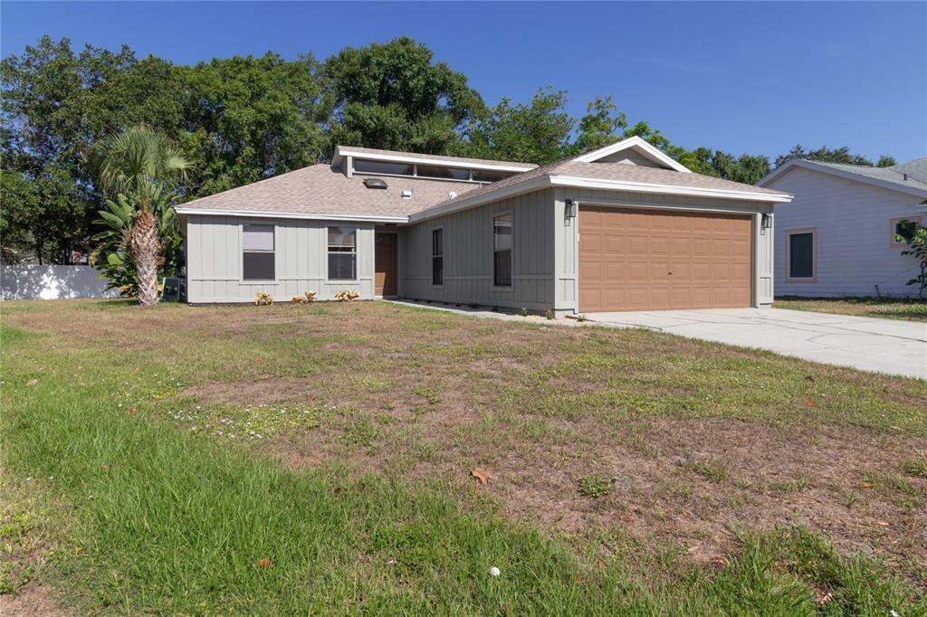 A single-story house with light gray siding, a brown garage door, and a grassy yard — 8232 COUNTRY OAKS COURT, SARASOTA, FL