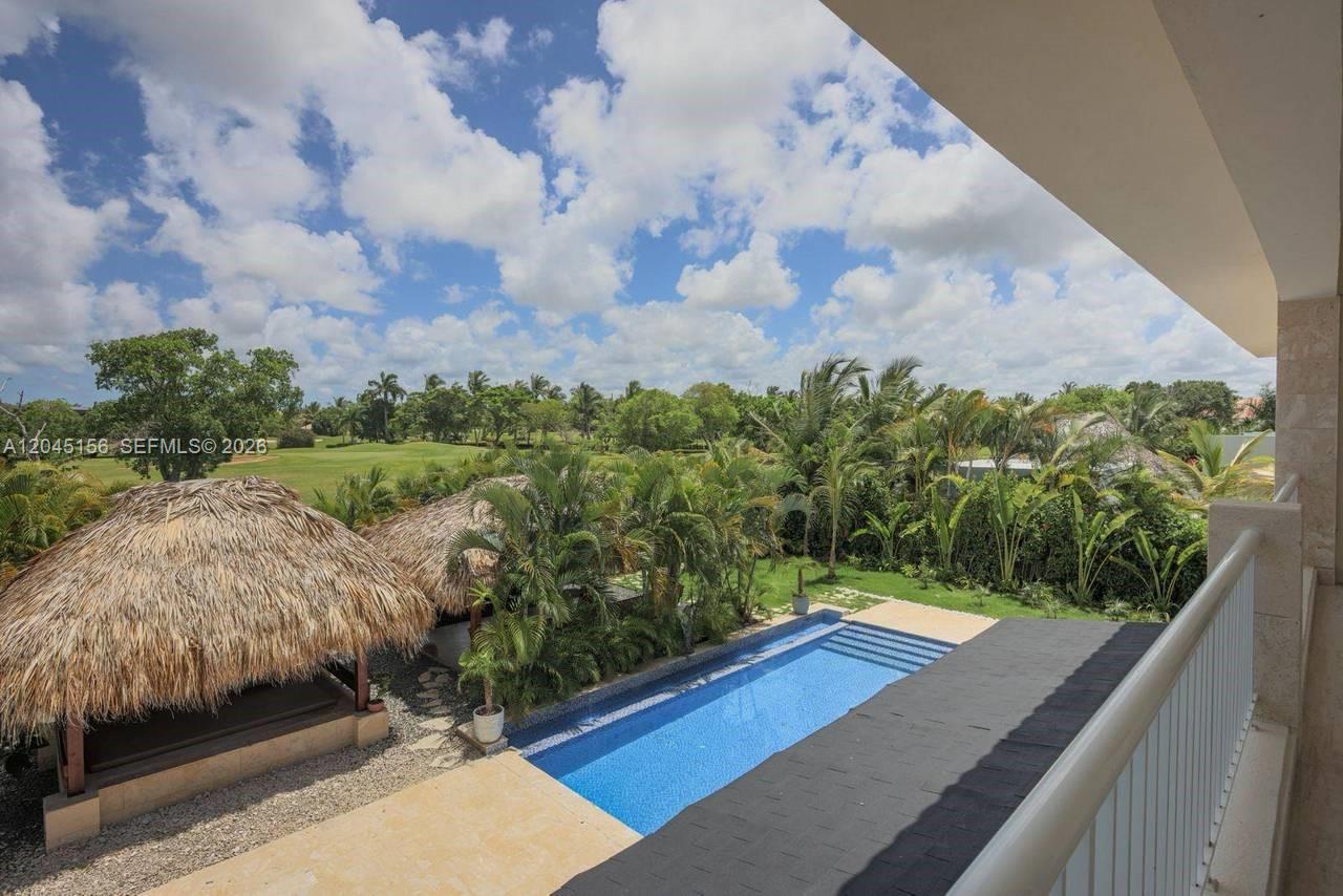 An elevated view shows a swimming pool, two thatched-roof gazebos, and a grassy golf course — 0 cocotal, FL
