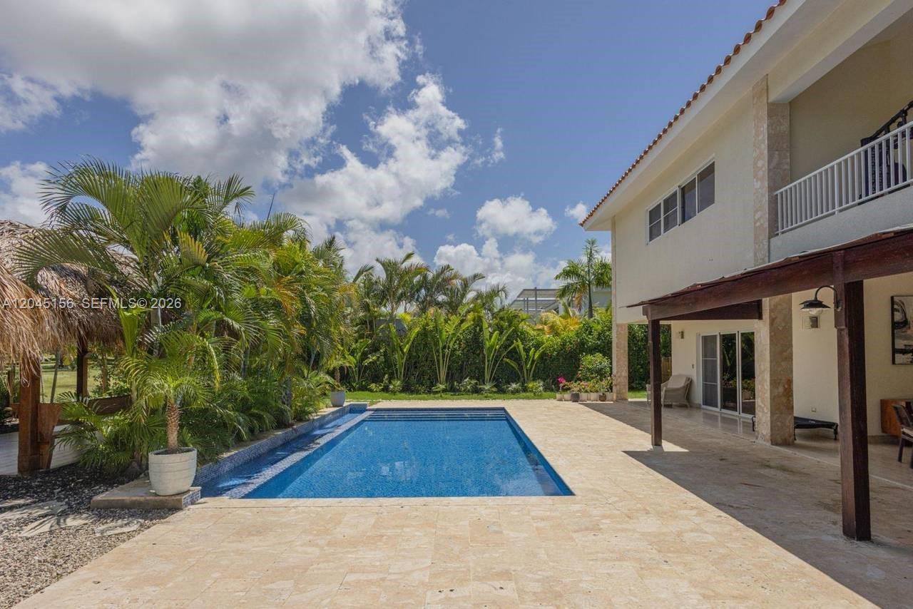 A rectangular swimming pool sits on a stone patio beside a two-story house — 0 cocotal, FL