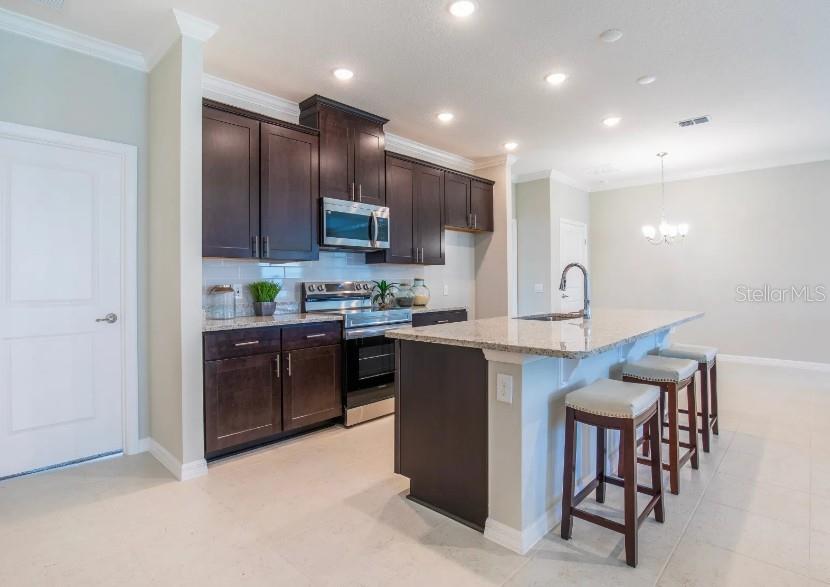 A kitchen features dark wood cabinets, granite countertops, a center island, and three bar stools — 17663 NW 169TH PLACE, ALACHUA, FL